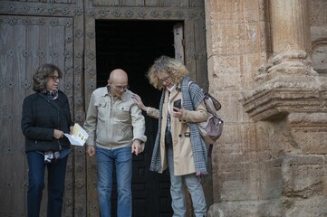 Three senior travelers observing and pointing at something intriguing on the ground near the Gothic...