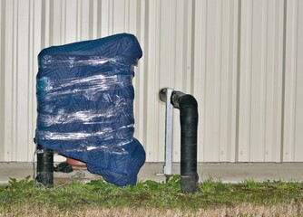 Wrapped pipes building exterior freezing weather protection winter storm.