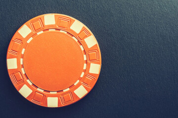 Naklejka premium Orange poker chip on a dark background ready for casino play and games