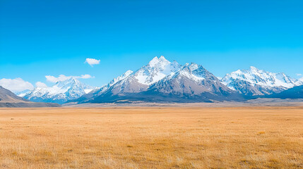 Fototapeta premium Snowy mountains and golden plains under a clear blue sky. Travel postcard