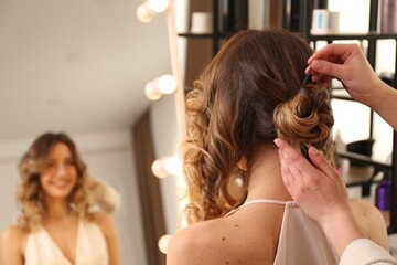 Naklejka premium Stylist working with client in salon, making hairstyle