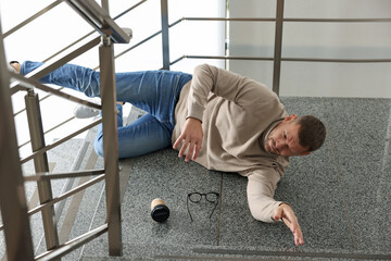 Injured man on stairs in building after fall. Dangerous accident