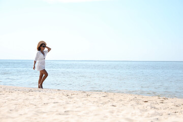 Young woman with beautiful body on sandy beach. Space for text