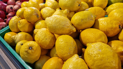 Sale of lemons in a supermarket. Citrus fruits in plastic boxes, close-up. Lemons in a store. Ripe, juicy, bright yellow lemons. A pile of lemons for sale at the market