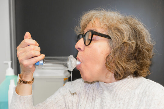 Mature woman using inhalation device for respiratory treatment