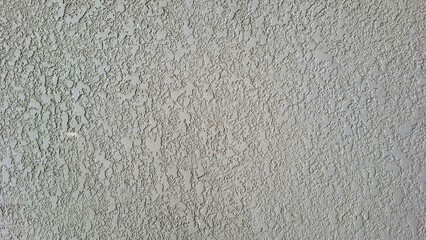 A grey wall with a lot of small holes and cracks