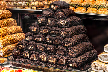 A pyramid of delicious Turkish delight, dark and richly textured, sits proudly displayed. Walnuts are visible within the sweet rolls. A tempting confectionery treat, perfect for food and recipe sites