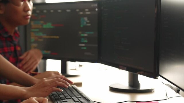 Slow motion back end software developer engineer for computer programming working together on debugging writing computing code, solving complex algorithms display on monitor in office. Burgeoning