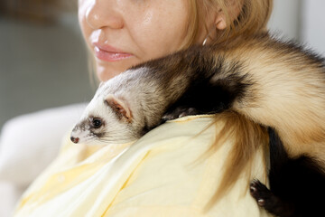 Woman with cute ferret on blurred background, closeup