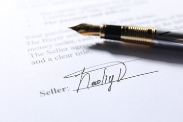 Signature and fountain pen on paperwork, closeup view