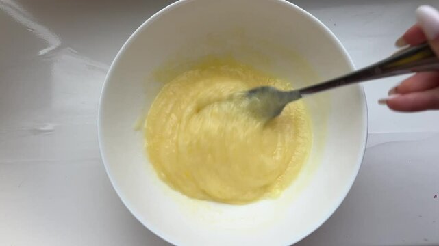 mix with a spoon fork and a woman's hand stirs an omelette baking dough prepares sauce white plate white table cook at home master class good food