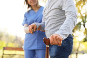Caregiver assisting senior man in park, closeup. Home health care service