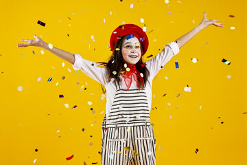 Happy girl dressed like mime under falling confetti on yellow background. Surprise party