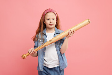Little girl with baseball bat on pink background