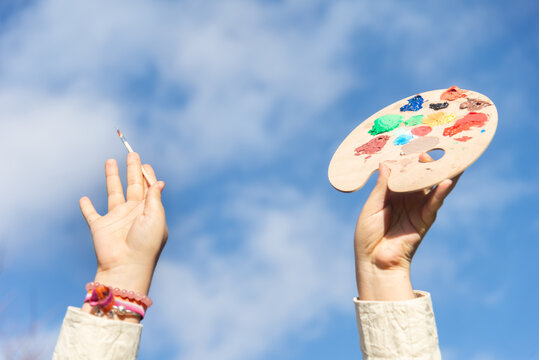 Creative expression with palette against vivid blue sky in the park