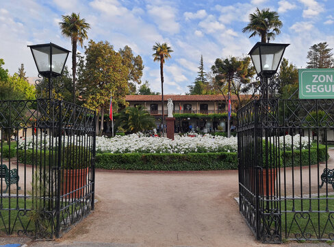 Gate, white flowers, and trees at the entrance of Casona de las Condes (Santiago, Chile)