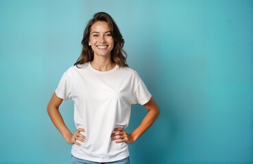 Young woman poses confidently in white t-shirt against blue background. Happy expression. Casual style. Mockup image. Perfect for design templates, branding. Attractive brunette female. Copy space