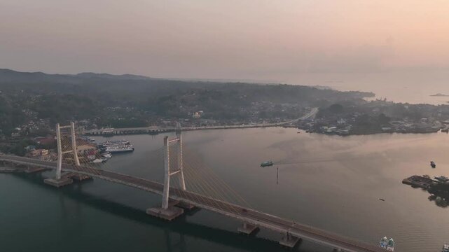 4k aerial footage of the sunset on the Kendari Bay Bridge which has become a tourist icon in Southeast Sulawesi, Indonesia. Golden yellow twilight aerial panorama of the iconic suspension bridge