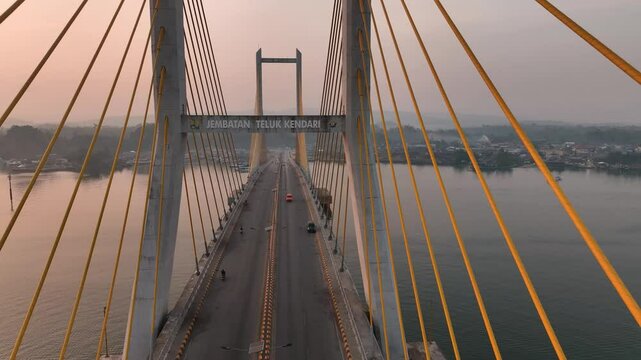 4k aerial footage of the sunset on the Kendari Bay Bridge which has become a tourist icon in Southeast Sulawesi, Indonesia. Golden yellow twilight aerial panorama of the iconic suspension bridge