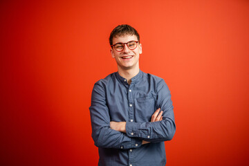 portrait of man stand arm crossed in front red background studio shot