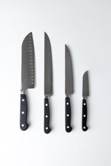 closeup background on a table lie steel straight kitchen knives of different calibers and sizes with a black handle, a housewife's set for various purposes, professional knives