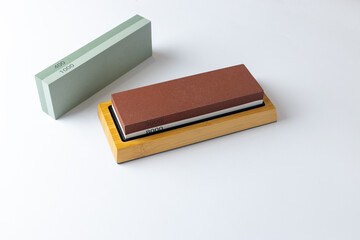 white background on table lies all the equipment a set for sharpening and polishing kitchen knives and various blades different abrasiveness of stones a retainer for knives