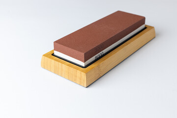 closeup white background on table lies red equipment a set for sharpening and polishing kitchen knives and various blades different abrasiveness of stones a retainer for knives