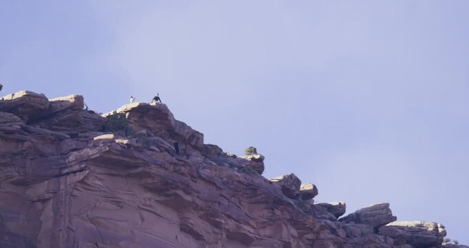 Silhouette of beautiful southern Utah rocky mountain cliff with parachuter jumping off in slow motion