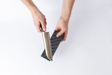 top shot on white background on a table man hands sharpen a steel knife protection against cuts, a black medium-hard stone for sharpening knives professional knife for slicing vegetables