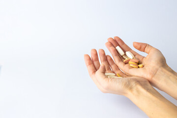 on white background, on the outstretched palms of female hands, there are pills and vitamins of different shapes and colors. suicidal thoughts, depression, health care.