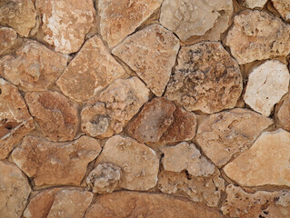 Beige and yellow natural stone masonry wall texture, irregular friable stones background for house walls, privacy dividing wall, facades. Stone and rock surface background in rustic style.