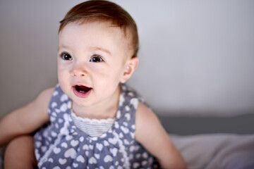 Naklejka premium Happy baby, girl and bed with playful childhood for youth, growth or development at home. Little kid, infant or adorable child with cute dress in bedroom for nursery or toddler relaxing at house