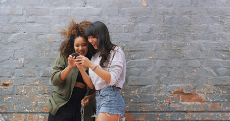 Wall, women and friends with smartphone, showing or excited for acceptance to college or...