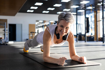 Smiling fitness An elderly gray-haired senior pensioner stand in plank position doing push