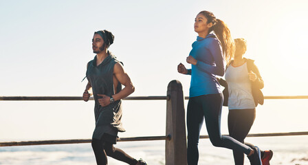Group, fitness and running with sunset by beach for cardio workout, exercise or training together...