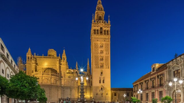 La Giralda and Seville Cathedral day to night transition timelapse, glowing with golden lights after sunset. The historic bell tower, gothic details and illuminated streets in Seville, Spain