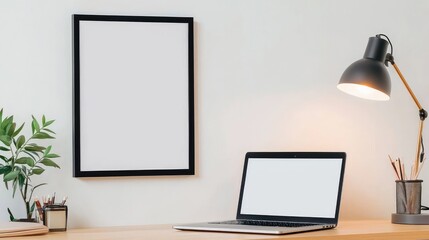 Modern Workspace with Laptop, Desk Lamp, and Empty Frame on Wall