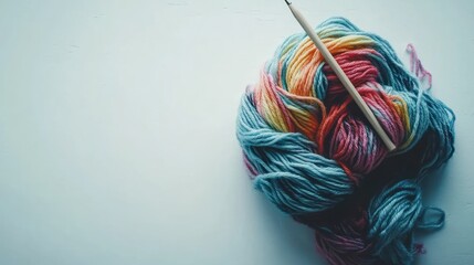 Colorful yarn ball with a knitting needle on a light surface.