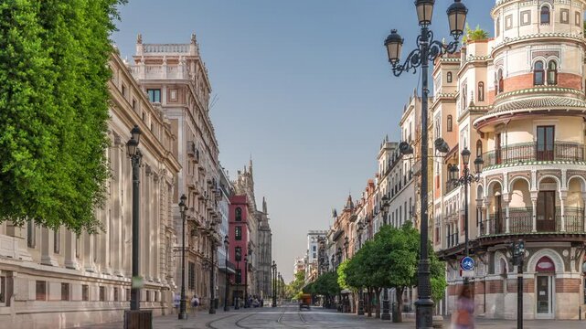 Pedestrians walking along Avda. de la Constitucion, major avenue in Casco Antiguo district of Seville, Spain. Timelapse near Edificio de la Adriatica, historical buildings and passing trams