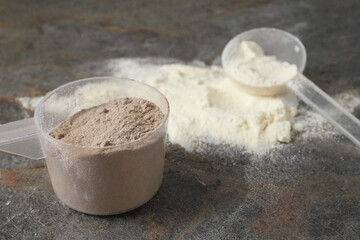 Protein powders and scoops on grey textured table, closeup