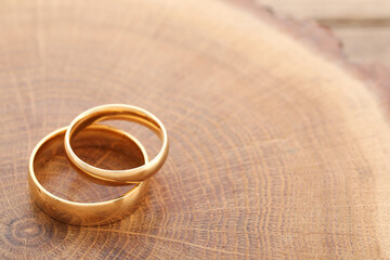 Beautiful golden wedding rings on wooden background, space for text