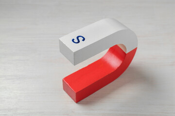 One horseshoe magnet on white wooden table, closeup