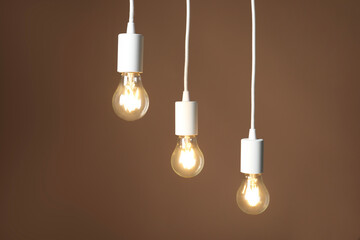 Light bulbs hanging on cords against brown background