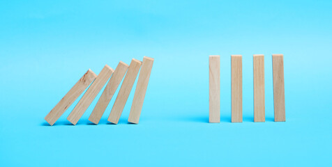 Domino effect. Wooden blocks falling on light blue background