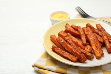 Delicious sweet potato fries and sauce on white wooden table, closeup. Space for text