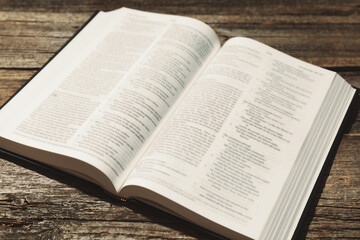 Open Holy Bible in English language on wooden table, closeup