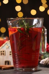 Tasty punch drink in glass jug on dark table against blurred lights, closeup