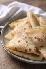 Delicious folded crepes on wooden table, closeup