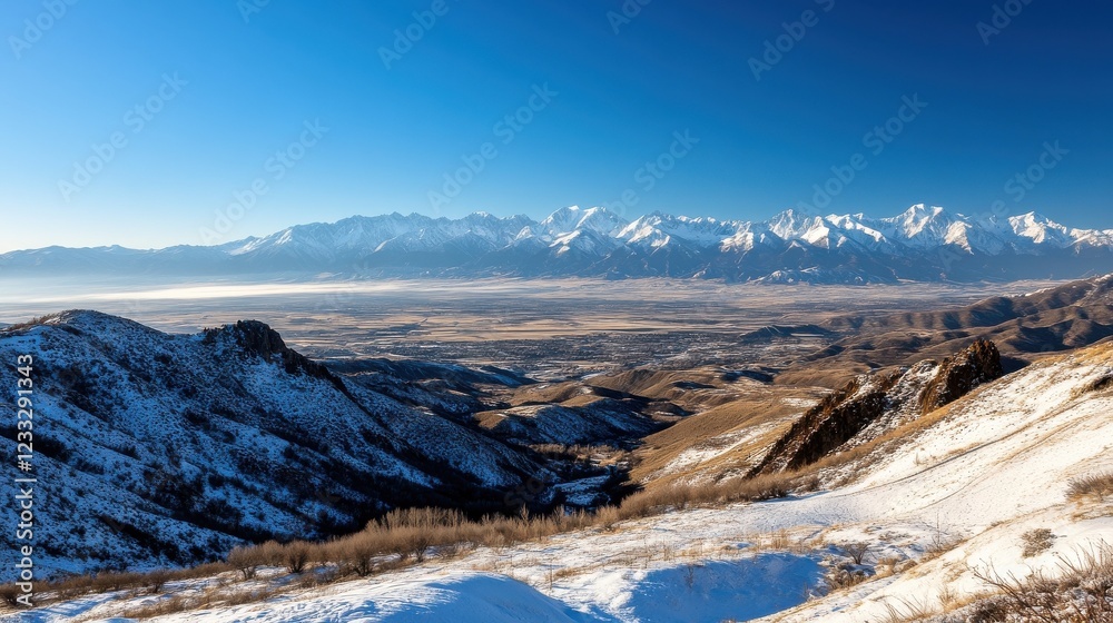 Poster an expansive view of a mountain range blanketed in snow under a clear blue sky.