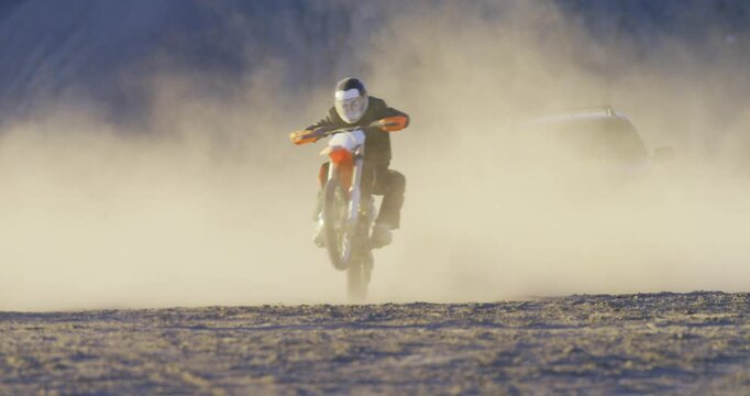 Motorcyclists doing wheelies through desert while being chased by van, steady cam